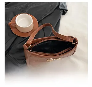 Top view of brown faux-crocodile shoulder bag with gold bow clasp on a lifestyle background