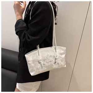Detailed view of white lace tote bag featuring 3D butterfly embroidery and leather straps