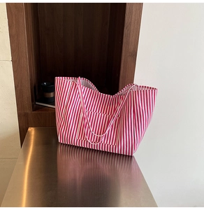 Detailed close-up of a red and white striped canvas tote bag with a front pocket
