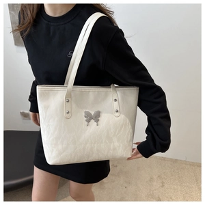 Detail of ivory white tote bag featuring metallic silver butterfly and wrinkled texture