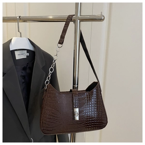 Detail of dark brown crocodile embossed shoulder bag with silver chain strap on a blazer