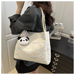Detail of white canvas bucket bag with colorful wavy embroidery and panda charm