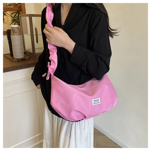 Close-up of pink pleated crossbody bag with ruffled strap worn by a model in a cafe