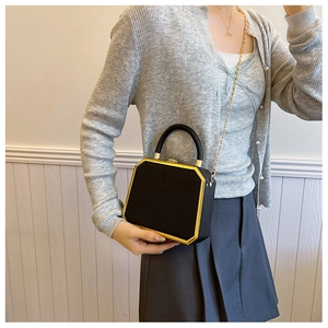 Detail of octagonal black leather box bag with gold metal frame and floral embossing