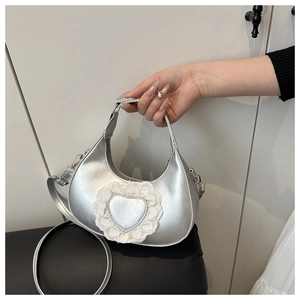 Detail of silver heart dumpling bag with white lace trim and metallic PU leather finish
