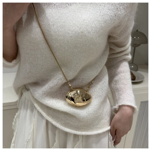 Detail shot of a minimalist gold shell-shaped hammer texture pendant on a model