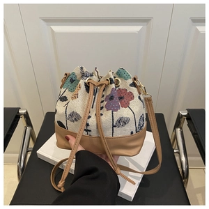 Detail of floral embroidery and brown leather base on a bohemian drawstring bucket bag