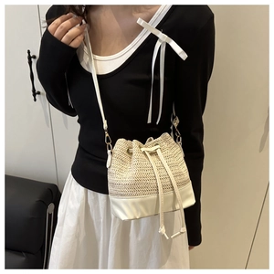 Detail of woven straw bucket bag featuring white leather drawstring and gold hardware