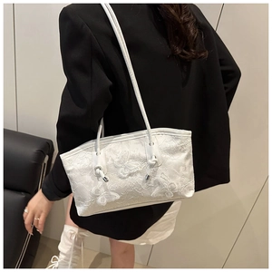 Detailed embroidery view of a white shoulder bag with 3D butterfly patterns and lace