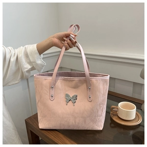 Detail of pink tote bag with pleated texture and silver butterfly ornament in soft light