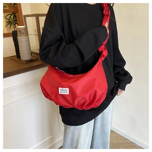 Close-up of a vibrant red nylon dumpling bag featuring a fashion label on the front