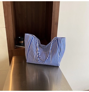 Detail view of a large blue and white striped canvas tote bag with front pocket and straps