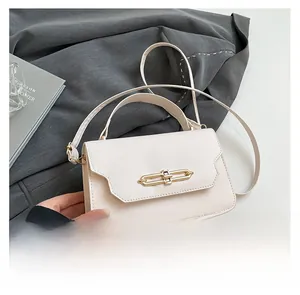 Detail of elegant cream crossbody bag with gold double-ring buckle and top handle