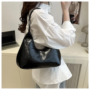 Detail view of a shiny black leather hobo bag worn with a white shirt for urban commute