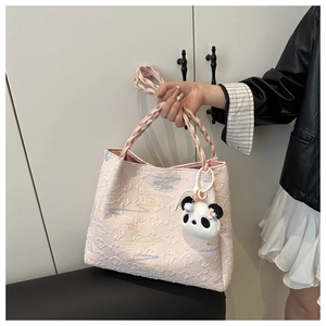 Detail of light pink jacquard tote bag with woven handles and cute panda plush charm