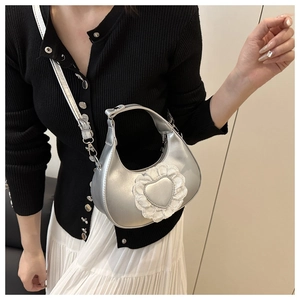 Detail of silver metallic hobo bag featuring white lace heart and adjustable strap