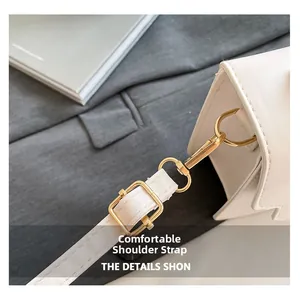Close-up of white lychee leather handbag with pale gold buckle and adjustable strap