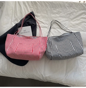 Close-up of striped canvas tote bags in red and black with front pocket and shoulder strap