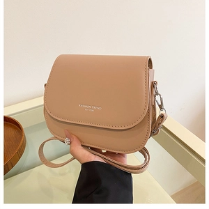 Minimalist crossbody saddle bag in nude PU leather with adjustable strap and front logo