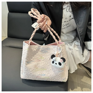 Detail of pink quilted tote bag with textured monogram fabric and panda plush charm