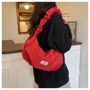 Détail du sac plissé rouge en nylon avec bandoulière à volants et étiquette de mode