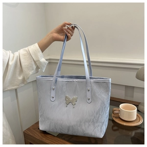 Detail of light blue tote bag with silver butterfly buckle on a dark wooden table