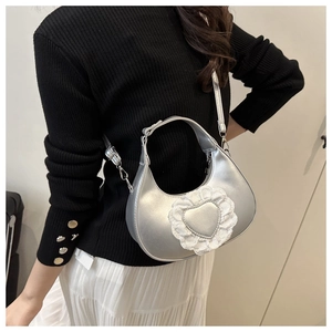 Detail of silver heart with white lace trim on metallic crescent crossbody bag