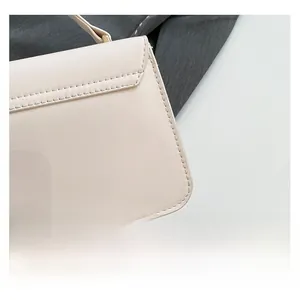 Detail shot of the cream leather handbag showing precise stitching and fine texture