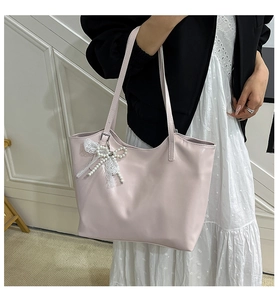 Detail of light pink tote bag with pearl and lace bow charm on model shoulder