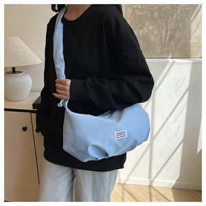Détail du sac croissant bleu clair avec étiquette mode et large bandoulière nouée