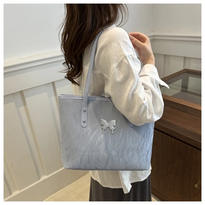 Detail of light blue tote bag with wrinkled texture and silver butterfly ornament