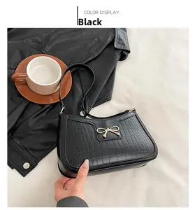 Detail of black crocodile texture bag with gold bow ornament and coffee set