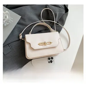 Detail of off-white crossbody bag with gold chain buckle and smartphone size comparison