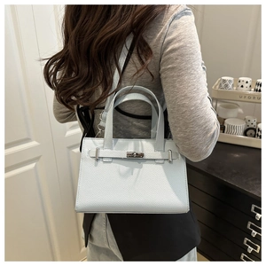 Detailed view of light blue lychee pattern leather tote bag with silver hardware on model
