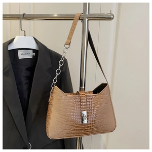 Detail of caramel crocodile embossed tote with silver chain strap and metal turn-lock