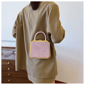 Detail of lavender floral embossed box bag with gold frame and elegant chain strap