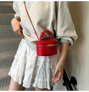 Close-up of red quilted mini crossbody bag with chain strap worn by a model