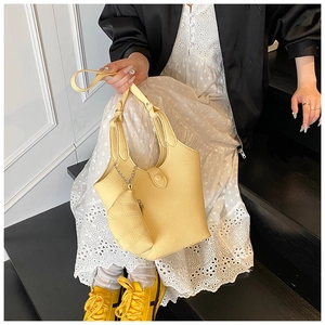 Detail of bright yellow pebble leather bucket bag with silver chain and matching charm