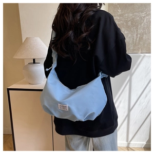 Vue détaillée arrière d'un sac bandoulière bleu clair avec étiquette blanche et texture souple