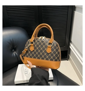 Detail of vintage shell bag with brown monogram pattern and caramel leather trim