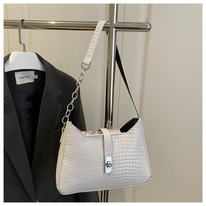 White baguette bag with crocodile texture and silver chain strap against a grey blazer
