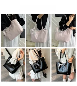 Detail of minimalist large tote bag with decorative pearl bow pendant in beige and black