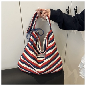 Detail of canvas tote bag with red, white, and blue stripes and a blue lace bow decoration