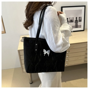 Macro view of black crinkle tote bag featuring a white 3D butterfly accent and thin straps