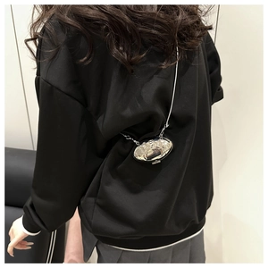 Détail du mini sac coquillage argenté avec chaîne porté comme accessoire de taille chic