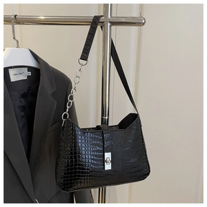 Detailed view of black crocodile pattern leather bag with silver metal chain strap