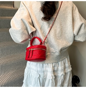 Close-up of a bright red quilted mini bucket bag with a golden chain and dual zippers