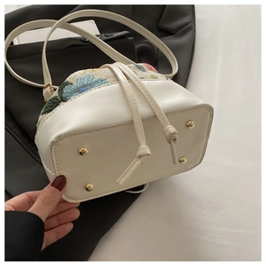 Detail view of ethnic bucket bag with floral tapestry and protective gold metal studs