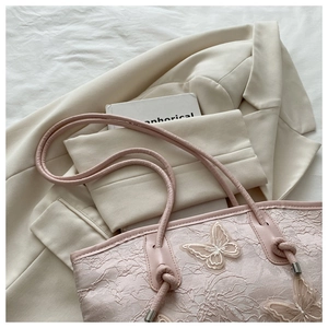 Detail of floral lace texture and 3D butterfly embroidery on the pink tote bag