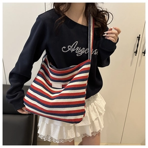 Détail du sac cabas en toile rayé rouge et bleu avec large bandoulière sur le modèle